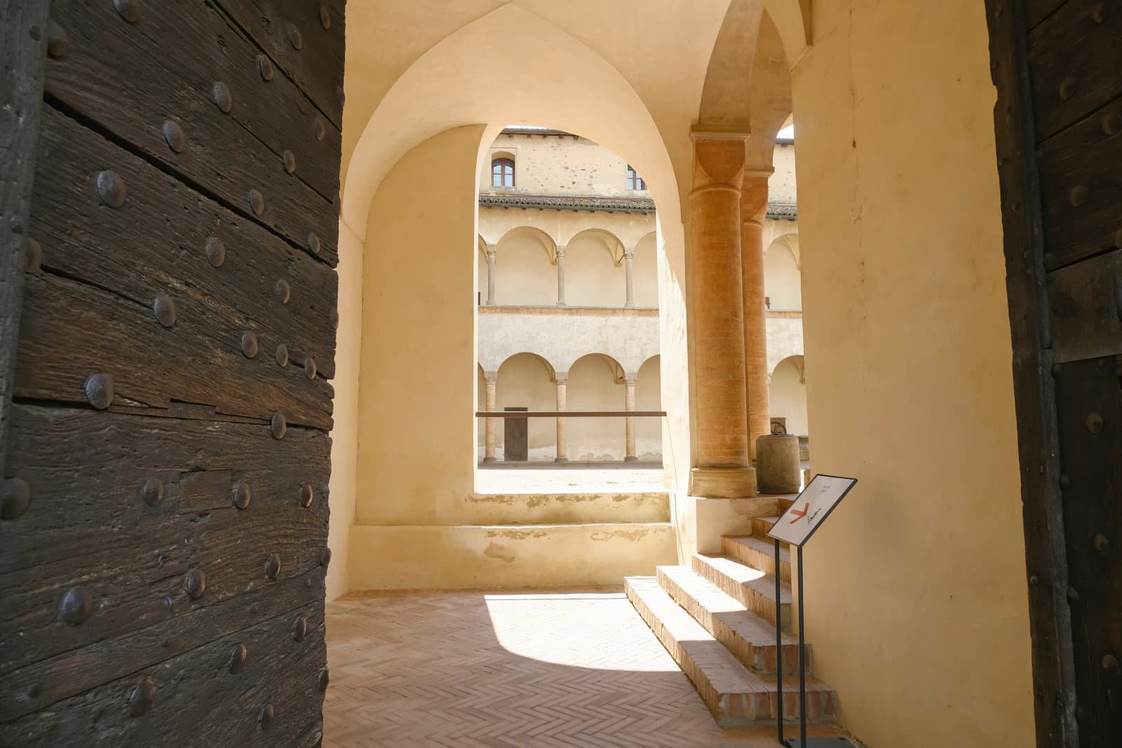 ancient wooden door on the entrance to the Castle Torrechiara in Langhirano, Italy across arches and columns inside