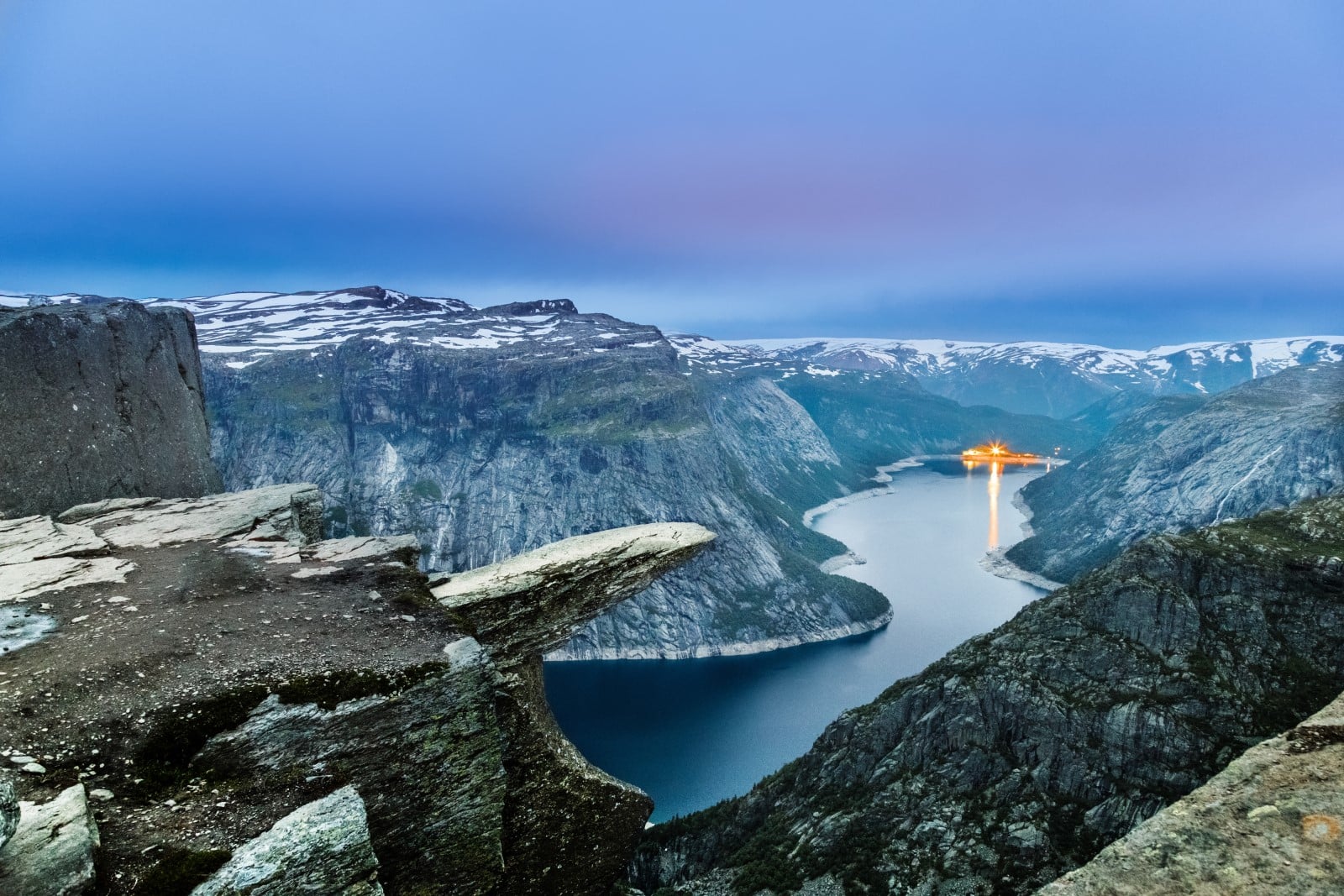 Trolltunga travel destination landmark. Twilight scene. Troll tongue in original norwegian Trolltunga is cliff above lake fjord in norwegian mountains, famous and popular destination for hikers.